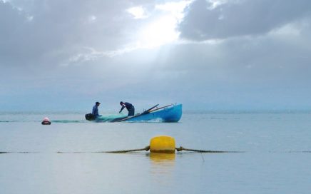 two fishermen out in a boat on the Kinneret with a buoy in front of the boat