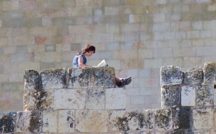 woman sitting on top of the wall surrounding the old City of Jerusalem