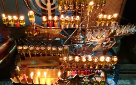 a lot of different hanukkiot, all lit up