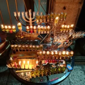 a lot of different hanukkiot, all lit up