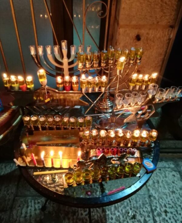 a lot of different hanukkiot, all lit up