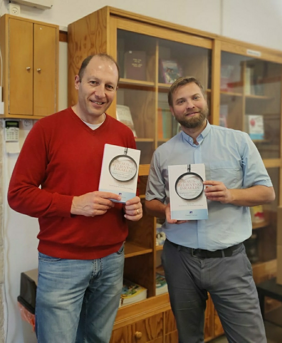 Two men holding new books. 